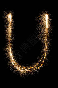 为你而来艺术字英文大字母U由黑色背景上的燃烧火花制成闪亮的节日派对烟花字体背景