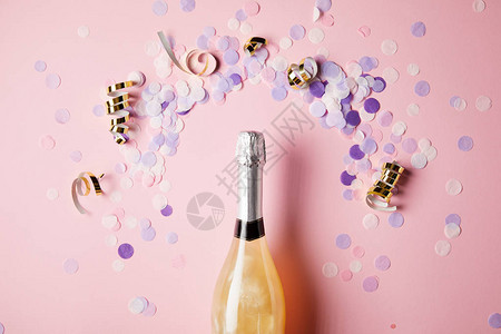 粉红色表面的香槟和彩色面粉图片