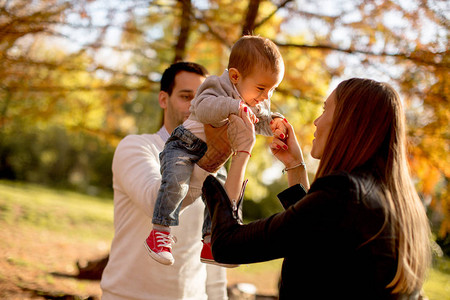 快乐的年轻父母在秋天公园和小图片