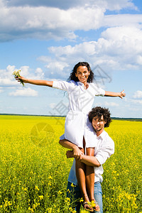 站在黄色草地中间的快乐男人肩上抱背景图片