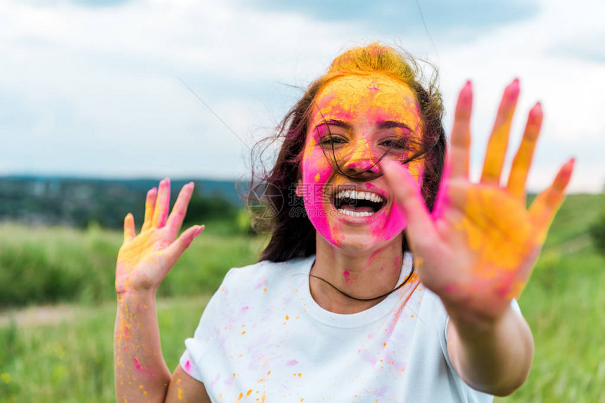 面和手上涂着粉和黄色胡利颜料的快乐妇图片