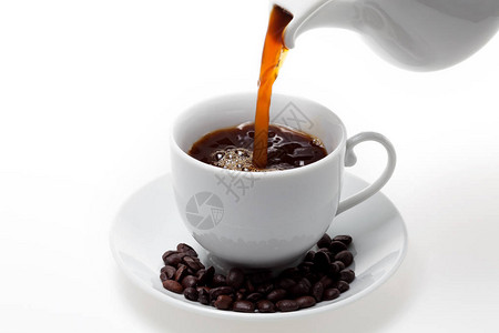 将咖啡倒入白咖啡杯和白色背景的豆子中图片