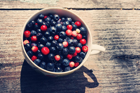 木制背景碗中的新鲜蓝莓和蔓越莓图片