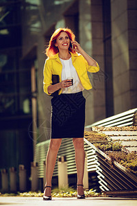 在办公区用智能手机喝咖啡休息时嘲笑成功的商业女商图片