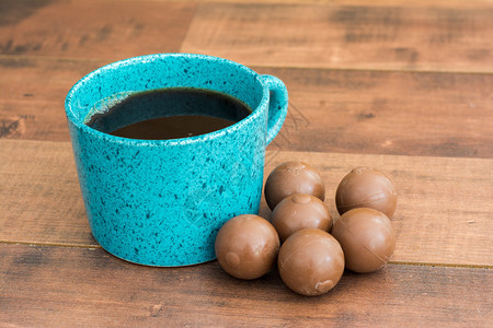 Teal咖啡杯满是黑咖啡和巧克力球图片