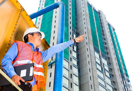 亚洲建筑工地上有剪贴板的建筑工人或图片