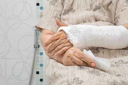 手臂骨折的老妇人用助行器上厕所图片