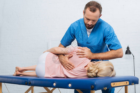 躺在医院按摩桌上的病人的脊椎调节器背部图片