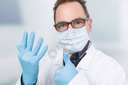 戴面罩的医生使用医疗手套图片