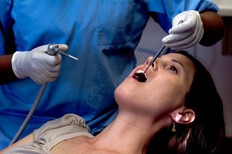 由专科牙医检查其牙齿的女病人单背景图片