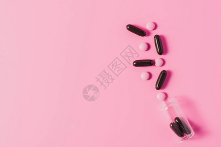 粉色和黑色药丸洒在粉色上的瓶图片