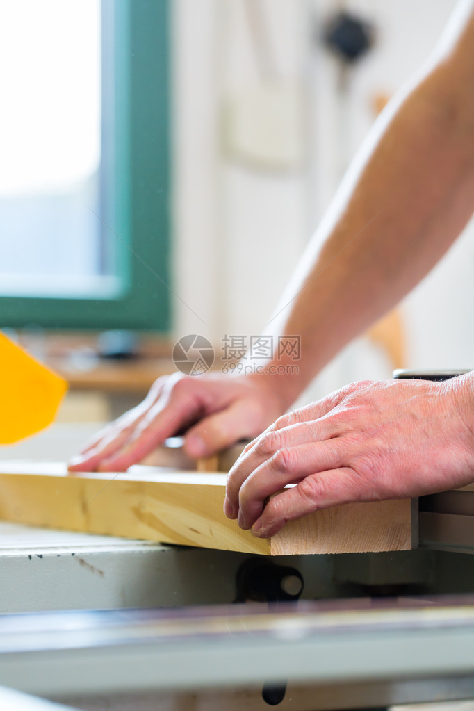 木匠在电动锯上工作并在木工中切割一些木板图片
