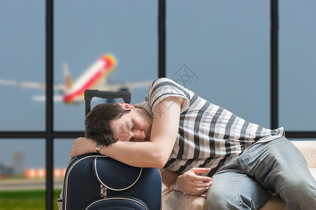 延误的飞机概念疲惫的乘客睡在机场航站楼的行李上图片