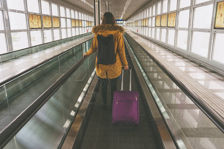 携带手提行李的年轻妇女在国际机场候机坪旅行图片