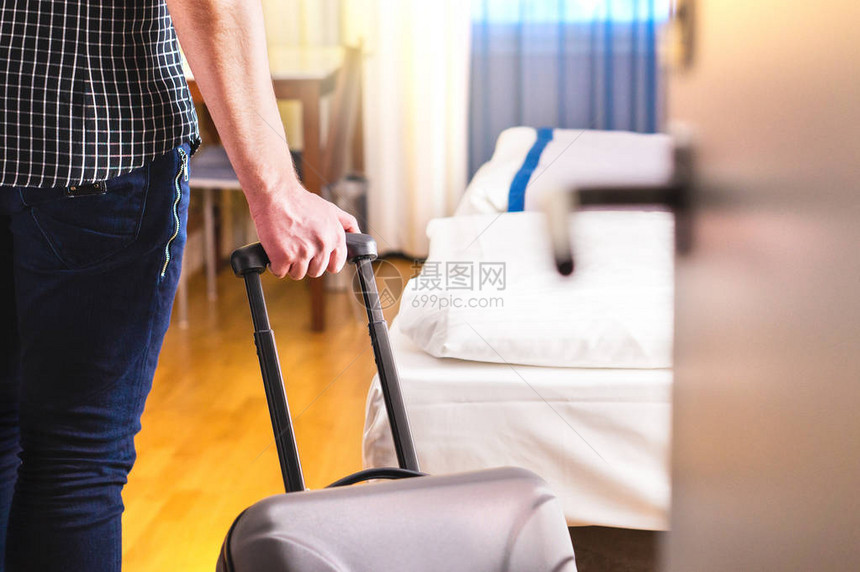 男人拉着手提箱进入酒店房间旅客进入房间或带着行李走进汽车旅馆旅行和度假图片
