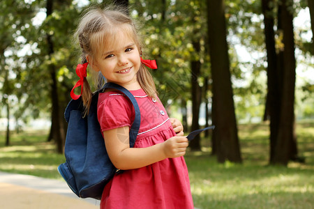 美丽的小女孩背着包走在公园里准备回到学校户外游图片