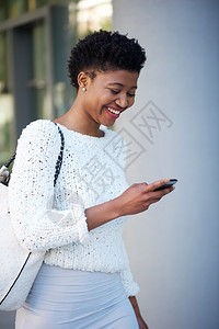 一个女人在外面走路看手机的画像图片