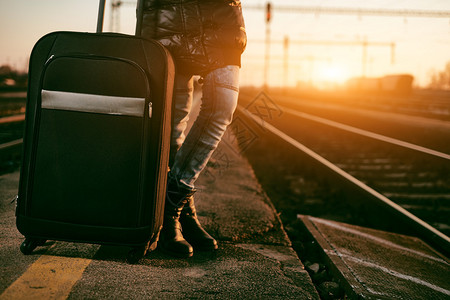 日落时在火车站带行李的旅图片