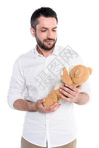 一个年轻的大胡子男抱着一只泰迪熊的半身照背景图片