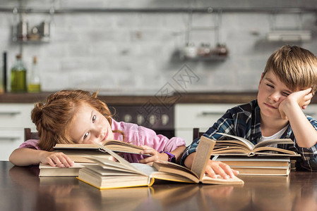 疲倦的小学者一边做作业一边睡在书上背景图片