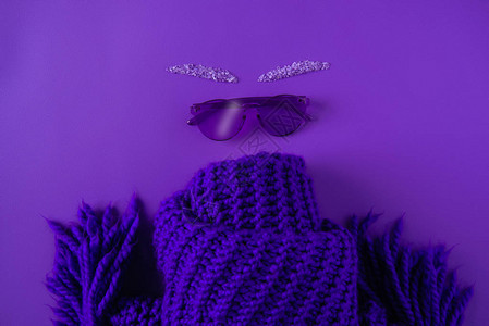 用紫色隔开的眼镜和围巾的顶视图背景图片