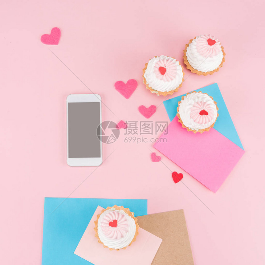最美味的纸杯蛋糕带空白屏幕的智能手机和粉红色的心脏符号图片