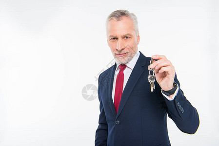 笑成熟的商人拿着钥匙看着在白色上被背景图片
