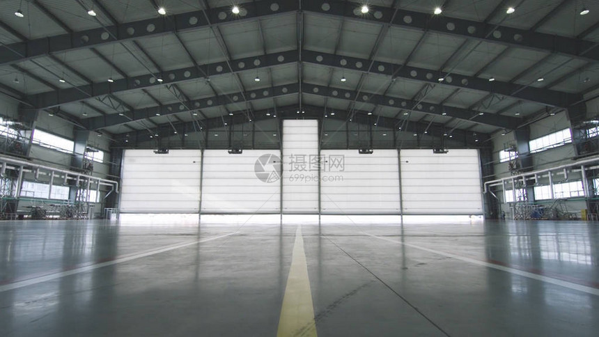 工业背景的厂房内的卷帘门和混凝土地板前面的飞机半开到机库的门机库敞开的门图片