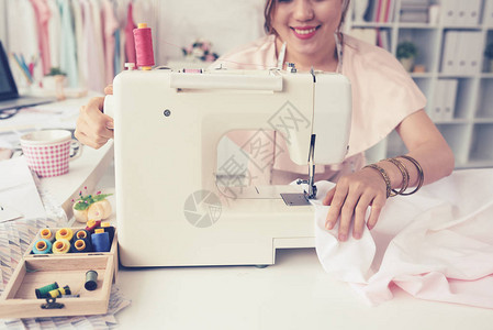 女裁缝在纫机上工作的裁剪图像图片