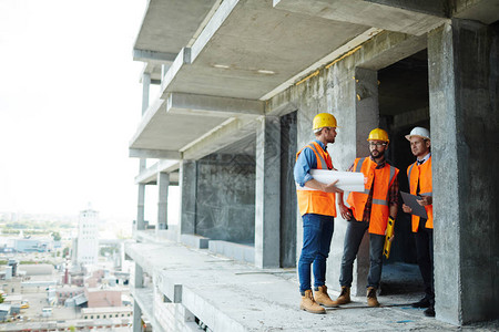 3个建筑师站在未完工大楼的一层楼图片