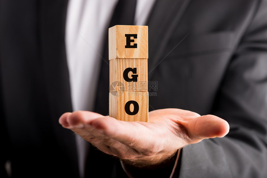 商人拿着木制字母块阅读Ego他手掌的平衡在概念上的形象图片
