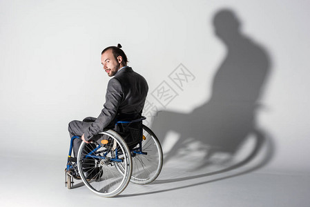 坐在轮椅上墙上有影子的年轻残疾青年个体背景图片