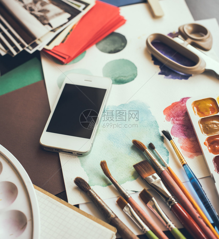 艺术家工作室桌上的智能手机水彩颜料画笔和草图调色板和绘画工具艺术与现代科图片