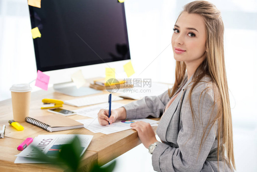 女营销经理在办公室工作场所做文书工作时看着