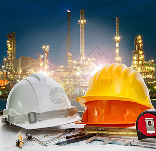 工程师工作台上的安全头盔对抗石油化厂用于能源电力和化石燃料行业的炼油图片