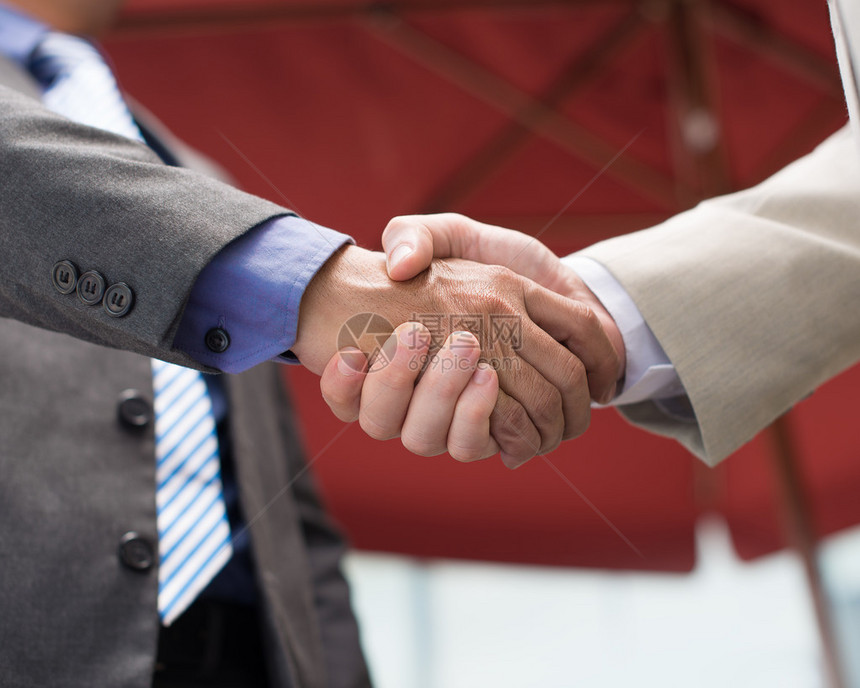 商业同事握手作为在前景问题上达成协议的标志而刻的图片