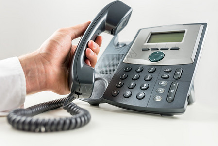商人拿着电话听筒准备在固定电话上打电话的特写镜头客户服务或电图片