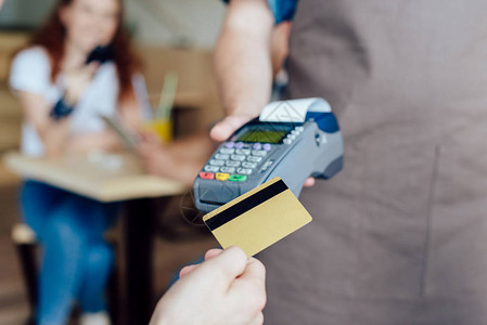 持信用卡和服务员持有付款终点站的个人客户的近视图片