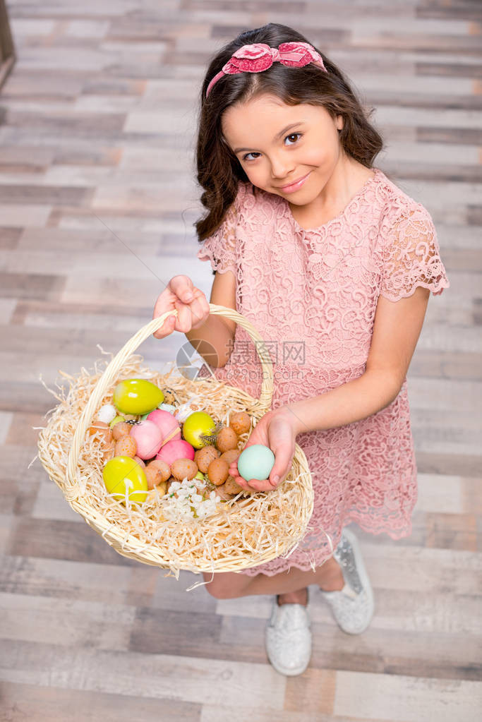 小姑娘拿着满篮子的彩色复活节鸡蛋图片