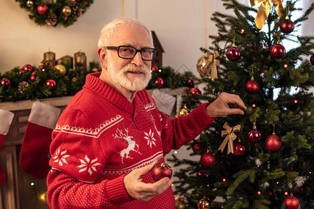老人用圣诞球装饰圣诞树图片