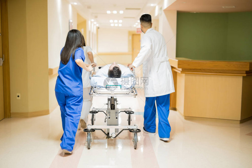 在医院用担架运送病人的一组医生的全长后方视线图片