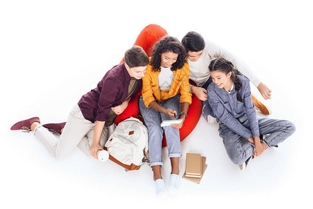 一群青少年学生坐在被白色隔离的豆袋上图片