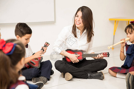 玩乐的学前女教师弹吉他向学生图片