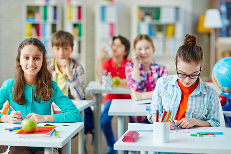 在教室上课时坐在课桌前的小学生背景图片