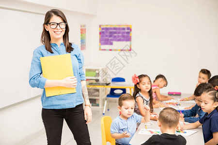 一名可爱的西班牙裔幼儿园教师在满教室学生的教室图片