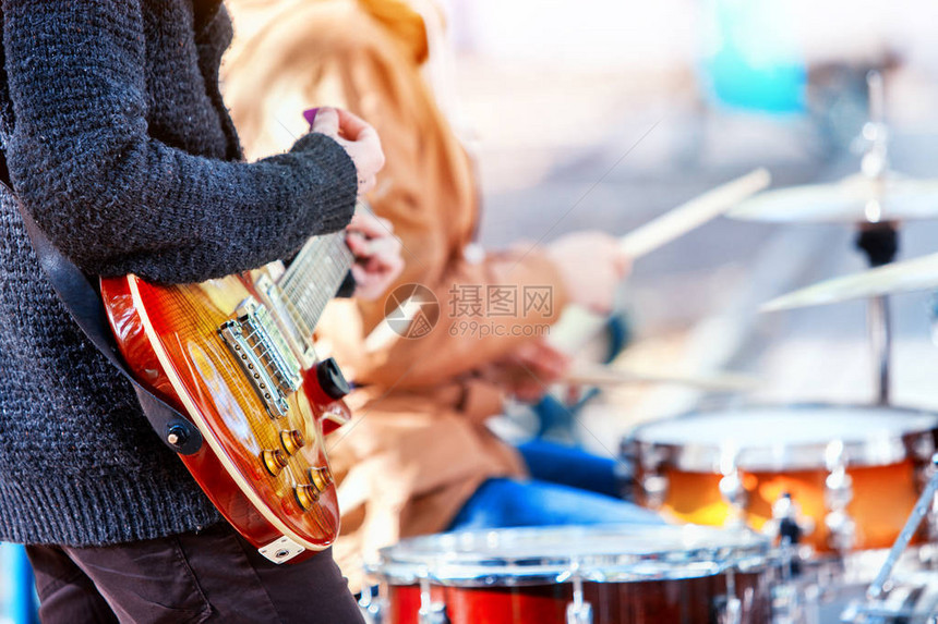 音乐队在城市公园里演奏打击乐器的手用棍子特写的鼓男音乐家的身体部位锐化是吉他和人的手图片