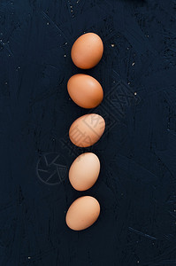 在深色背景上以直线排列的鸡蛋俯视图图片