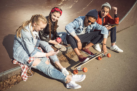 青少年小组坐在一起在滑板公园背景图片