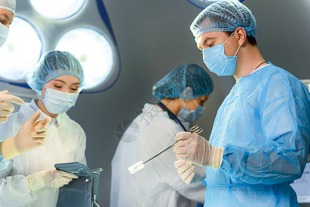 注意的男外科医生拿着夹子往下看医生在手图片