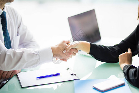 在办公室开会或谈判时的商务握手合作伙伴因签署合同或财务文图片